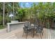 Outdoor kitchen and dining area with grill, sink, modern table and lush landscaping at 1742 Temple Dr, Winter Park, FL 32789