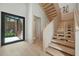 Modern staircase with open design, light wood treads, and a view to the outside courtyard through a black-framed glass door at 1742 Temple Dr, Winter Park, FL 32789