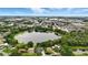 Expansive aerial view of a serene lake surrounded by lush greenery, residential homes, and commercial area at 2154 Lake Christie Dr, Orlando, FL 32809