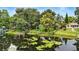 Scenic lake view featuring a wooden dock, green backyard with chairs, lily pads and surrounding trees at 2154 Lake Christie Dr, Orlando, FL 32809