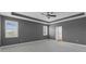 Bedroom featuring tray ceilings, neutral walls, and large windows with bright natural light at 32004 Redtail Reserve Blvd, Sorrento, FL 32776