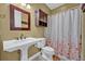 Traditional bathroom with a pedestal sink, toilet, cabinet and a floral shower curtain at 419 Whitcomb Dr, Geneva, FL 32732