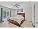 Bright main bedroom with hardwood floors, a ceiling fan, a king-sized bed, and access to the screened in lanai at 443 Magpie Ct, Poinciana, FL 34759