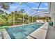 Relaxing screened in pool with clear blue water, surrounded by white patio, and beautiful green scenery at 443 Magpie Ct, Poinciana, FL 34759