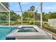 Spa is partially covered and set in a screened enclosure surrounded by lush landscaping at 443 Magpie Ct, Poinciana, FL 34759