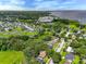 Wide aerial shot showing a single-story home in a green, wooded neighborhood with a lake in the distance at 525 Garden Heights Dr, Winter Garden, FL 34787