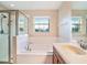 Bathroom features vanity, mirror, window, soaking tub, shower with glass door and tile flooring at 5917 Coquyt Dr, Mount Dora, FL 32757