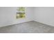 Bright bedroom with gray carpet, white walls, and a window overlooking the outdoors at 5990 Se 5Th Pl, Ocala, FL 34472