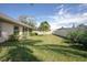 Large, grassy backyard featuring a privacy fence, trees, and an exterior view of the house at 710 Independence Dr, Orange City, FL 32763