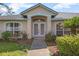 Close-up of the front entrance featuring double doors, arched windows, and manicured landscaping at 710 Independence Dr, Orange City, FL 32763