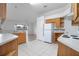 Well-lit kitchen features white appliances, oak cabinets, and tile floors, with a view into the living area at 710 Independence Dr, Orange City, FL 32763