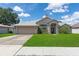 Charming single-story home featuring a manicured lawn, arched entryway, and an attached two-car garage at 1154 Feather Dr, Deltona, FL 32725
