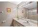 This bathroom features a double vanity, a large mirror with decorative lighting, and shower at 1225 Hollow Pine Dr, Oviedo, FL 32765