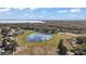 Wide aerial view of a beautiful community pond nestled among trees and houses near a tranquil lake at 12419 Eryn Ct, Clermont, FL 34711