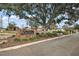 Inviting brick entrance sign for The Oranges community with mature landscaping and trees at 12419 Eryn Ct, Clermont, FL 34711