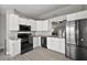 Updated kitchen featuring white cabinets, granite countertops, modern appliances, and wood-look tile flooring at 12419 Eryn Ct, Clermont, FL 34711