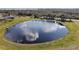Aerial view of a large pond with fountain, surrounded by lush greenery, and views of the surrounding landscape at 12419 Eryn Ct, Clermont, FL 34711