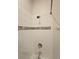 Close-up of tiled shower with a mosaic accent stripe, shower head, and faucet at 1259 Pando Loop, Orlando, FL 32824