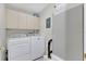 Bright laundry room with white washer and dryer and overhead storage cabinets at 1288 Americana Pl, Orlando, FL 32807