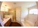 Bathroom with double sink vanity, soaking tub, wood floors, and gold trimmed shower at 130 Winsor Ave, Davenport, FL 33837