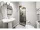 Bathroom showcasing a pedestal sink, oval mirror, and a glass door shower with tiled accents at 1443 Stone Trl, Enterprise, FL 32725