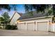 Three-car garage with elegant exterior lighting and an adjacent driveway with landscaping at 1443 Stone Trl, Enterprise, FL 32725