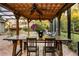 Covered outdoor dining area featuring a spacious wooden table, chairs, ceiling fans, and a view of the pool and surrounding greenery at 1443 Stone Trl, Enterprise, FL 32725