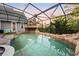 Screened-in pool area with a rock waterfall feature, lush landscaping, and a serene atmosphere at 1443 Stone Trl, Enterprise, FL 32725