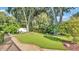 Lush backyard featuring a pristine artificial lawn surrounded by mature trees and manicured landscaping at 1455 Royal Forest Loop, Lakeland, FL 33811