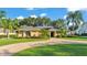 Charming single-story home featuring a circular brick driveway and lush, tropical landscaping at 1455 Royal Forest Loop, Lakeland, FL 33811