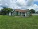 Green house with a covered porch and well-maintained lawn, showcasing a classic design at 1519 Illinois Ave, St Cloud, FL 34769