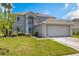 Charming two-story home with a well-manicured lawn and a two car garage on a sunny day at 16243 Wilkinson Dr, Clermont, FL 34714