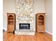 Bright living room features hardwood floors, a stone fireplace, and charming bookcases, perfect for a cozy gathering space at 173 Tollgate Br, Longwood, FL 32750