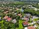 A beautiful home nestled among mature trees in a lush community with a pond and other homes with terracotta tile roofs at 1813 Glenbay Ct, Windermere, FL 34786