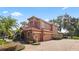Side exterior featuring an attached three-car garage, lush landscaping, and a winding brick pathway at 1813 Glenbay Ct, Windermere, FL 34786