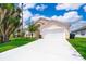 Charming single-story home with a well-manicured lawn, bright driveway, and attached two-car garage at 207 Langham Dr, Davenport, FL 33897