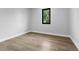 A simple, empty bedroom with light hardwood floors and a bright window providing natural light at 2300 S Brown Ave, Orlando, FL 32806