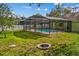 Large backyard with a screened pool enclosure, fire pit, and plenty of space for outdoor activities at 2351 El Prado Ter, Deltona, FL 32725
