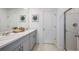 Clean, white bathroom with double sink vanity, neutral tiling, and walk-in shower at 325 Cornerstone Dr, Groveland, FL 34736