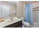 Well-lit bathroom with vanity, mirror, toilet, and shower with blue decorative curtain at 5172 Oakbourne Ave, Davenport, FL 33837