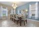 Formal dining room with seating for ten, soft blue walls, modern chandelier, and ample natural light at 5172 Oakbourne Ave, Davenport, FL 33837