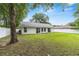 View of the home's back exterior showcasing a well-kept lawn, sliding glass doors, and a white fence at 5430 Nw 55Th Pl, Ocala, FL 34482