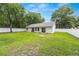 View of the home's back exterior showcasing a well-kept lawn, sliding glass doors, and a white fence at 5430 Nw 55Th Pl, Ocala, FL 34482