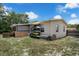 View of the home's backyard featuring a screened porch, outdoor storage, and lush greenery at 565 S Floyd Cir, Deltona, FL 32725
