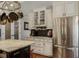 Well-lit kitchen features stainless steel refrigerator, custom cabinets, granite countertops, and hanging pot rack at 5740 Aloma Woods Blvd, Oviedo, FL 32765