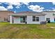 Exterior backyard view of house with covered patio and grassy lawn under a sunny sky at 8618 Sw 46Th Ave, Ocala, FL 34476