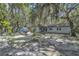 View of the rear of the home highlighting the spacious backyard with mature trees and an outdoor dining area at 10359 Smyrna Dr, Orlando, FL 32817