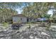 The backyard has mature trees, a picnic table, and the rear of the home with trash bags and yellow chairs at 10359 Smyrna Dr, Orlando, FL 32817