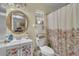 Bright bathroom with a vanity sink, round mirror, toilet and floral shower curtain at 10359 Smyrna Dr, Orlando, FL 32817