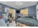 Blue bedroom with black metal bed, gaming chair, and TV setup at 10359 Smyrna Dr, Orlando, FL 32817